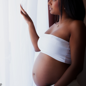 Pregnant woman smiling and holding her belly, radiating happiness and anticipation.